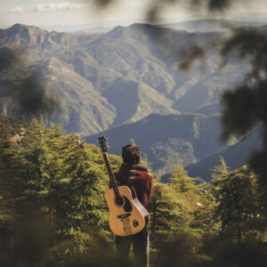 Mann mit Gitarre vor Gebirge
